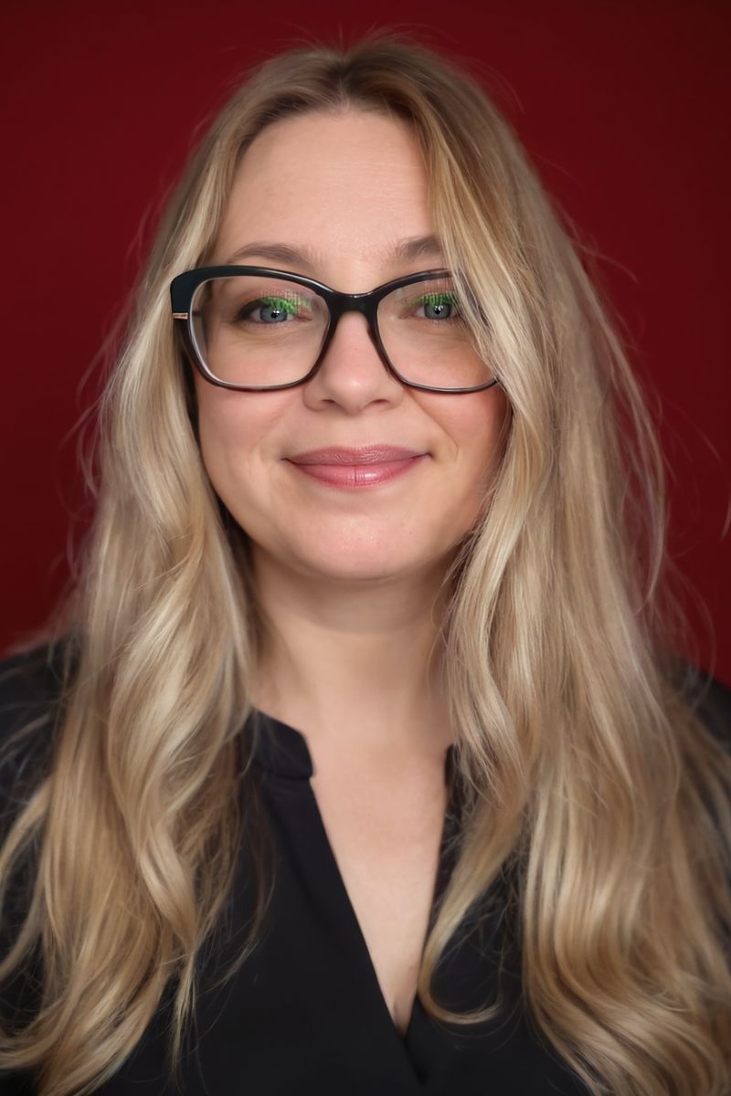 Gina Dunn, brand strategist and founder of OG Solutions, smiling in a professional headshot against a red background